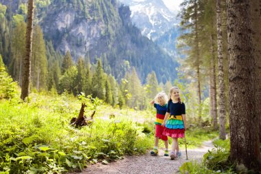 Alp dağlarında hiking çocuk. Karla kaplı dağ Avusturya, güneşli ormandaki çocuklar oynar. Bahar aile tatili. Küçük erkek ve kız doğal zammı izinde. Açık eğlenceli ve yaz etkinliği.