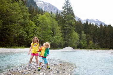Nehri geçerken Alp dağlarında hiking çocuk. Çocuklar su Avusturya Mountain oynamak. Bahar aile tatili. Küçük erkek ve kız zammı izinde. Açık eğlenceli. Çocuklu Aktif istirahat.