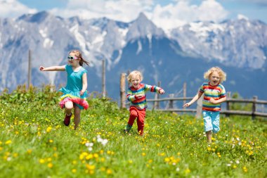 Alp dağlarında yürüyüş yapan çocuklar. Avusturya 'da karla kaplı dağda çocuklar koşar. Bahar tatili. Küçük bir çocuk ve kız dağ çayırlarında yürüyüş yolundalar. Açık hava eğlencesi ve sağlıklı aktivite