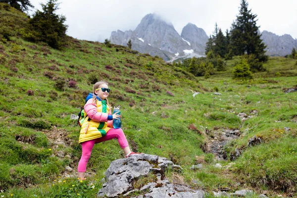 孩子们在阿尔卑斯山中远足 孩子们看着奥地利覆盖着积雪的山 小女孩走在盛开的高山草甸的小径上 户外运动的乐趣和健康 — 图库照片
