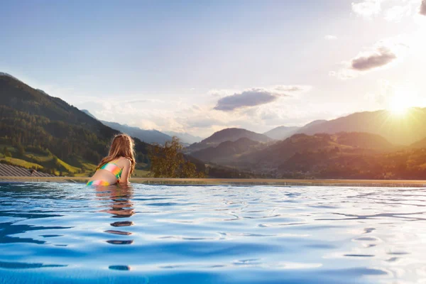在阿尔卑斯山的日落时分 孩子们在豪华温泉高山度假胜地的室外无限大游泳池里玩耍 有子女家庭的春假或暑假 男孩和女孩在有山景的热浴缸里 — 图库照片