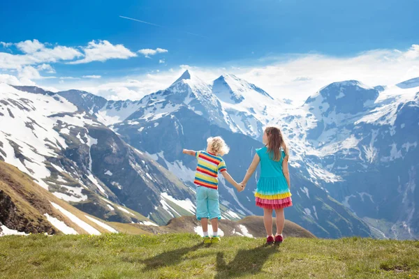 在阿尔卑斯山的孩子徒步旅行 孩子们看着奥地利积雪覆盖的山 春天的家庭假期 小男孩和女孩在远足小径在盛开的高山草甸 户外娱乐和健康活动 — 图库照片