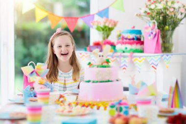 Doğum günü partisi renkli gökkuşağı pastel dekorasyon ve bunny katman pasta ile çocuklar. Küçük kız tatlı, şeker ve meyve ile. Balonlar ve afiş çocuk veya Bebek Doğum günü için şenlikli bir şekilde dekore edilmiş masada.