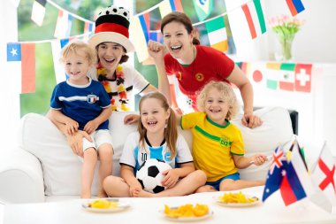 Televizyonda futbol maçı izlerken çocuklu aile. Grup Genç yetişkinler ve çocuklar Ulusal Triko izle futbol maçı televizyonda. Tezahürat ve ülke Takım Şampiyonası'nda destekleyen hayranları.
