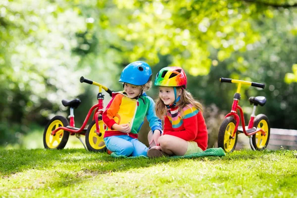 子供たちは バランスの自転車に乗って 日当たりの良い公園で自転車に子供 小さな女の子と男の子の暖かい夏の日にグライダー自転車に乗る バランスをとることを学ぶ幼児は 安全なヘルメットで自転車を実行します 子供のためのスポーツ — ストック写真