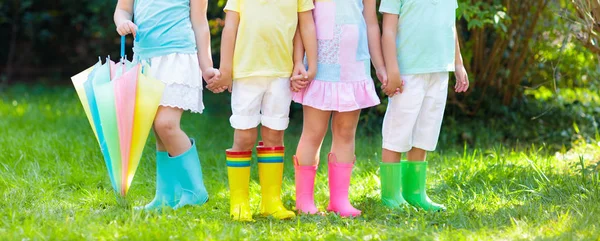 雨のブーツの子供たち カラフルなゴムブーツや秋のジャケットで幼稚園の子供たちのグループ 雨の秋のための履物 子供や赤ちゃんのための足の摩耗 ウェリーの幼児 レインボーガンブーツ キッドファッション — ストック写真