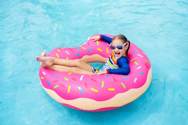 面白い膨らませてドーナツ浮き輪のプール内の子 トロピカル リゾートの屋外プールで泳ぐことを学ぶ少女 子供のためのおもちゃを水します 子供のための健康的なスポーツ活動 太陽の保護 — ストック写真