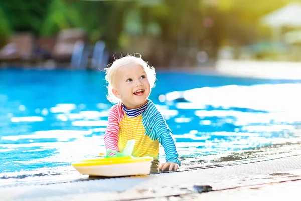 婴儿玩具船在游泳池 小男孩在热带度假村的户外泳池里学习游泳 和孩子们一起游泳 儿童健康体育活动 防晒游泳服 水上玩具 — 图库照片