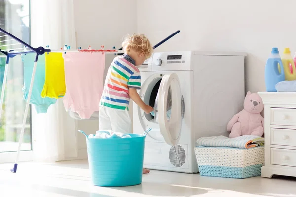 儿童在洗衣房内设有洗衣机或滚筒烘干机 帮助家庭琐事的孩子 现代家庭设备和洗涤洗涤剂在白色阳光的家 烘干机架清洗洗衣服 — 图库照片