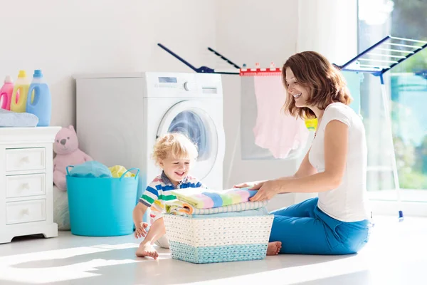 母亲和孩子在洗衣房里用洗衣机或滚筒烘干机 家庭琐事 现代家庭设备和洗涤洗涤剂在白色阳光的家 烘干机架清洗洗衣服 — 图库照片