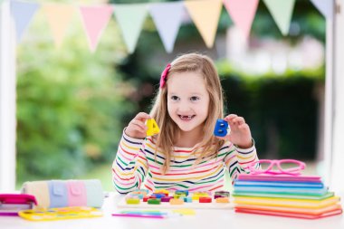 Çocuk okulda beyaz Resepsiyon için ödev. Ahşap eğitici abc oyuncak çocuklar için bulmaca. Geri okul öğrenci için çok mutluyum. Çocuk alfabesi harfleri öğrenme. Okul malzemeleri ve kitap ile küçük kız.