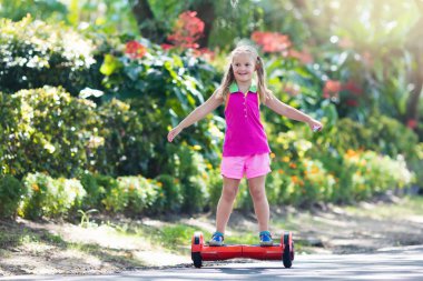 Vurgulu kurulu çocuk. Çocuklar yaz Park sürme. Çocuklar için denge kurulu. Elektrik kendini şehir sokak motorla Dengeleme. Kız Hoverboard binmek için öğrenme. Okul çocuk için modern araçlar.
