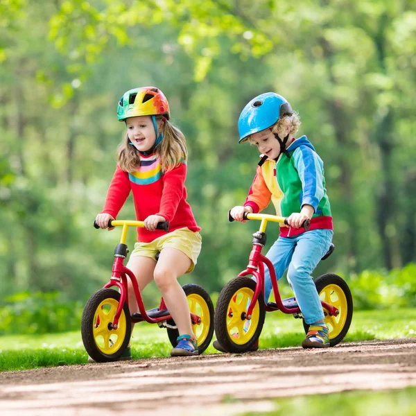 子供たちは バランスの自転車に乗って 日当たりの良い公園で自転車に子供 小さな女の子と男の子の暖かい夏の日にグライダー自転車に乗る バランスをとることを学ぶ幼児は 安全なヘルメットで自転車を実行します 子供のためのスポーツ — ストック写真