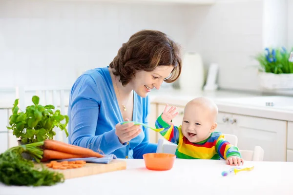 妈妈的喂养孩子 第一种固体食品年轻的孩子 新鲜的有机胡萝卜蔬菜吃午饭 断奶的婴儿 妈妈和小男孩多吃蔬菜 儿童的的健康营养 父母给孩子 — 图库照片