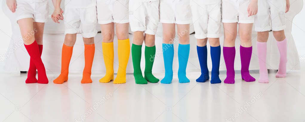 Kids wearing colorful rainbow socks. Children footwear collection. Variety of knitted knee high socks and tights. Child clothing and apparel. Kid fashion. Legs and feet of little boy and girl group.