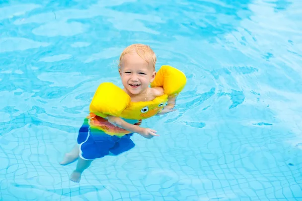 婴儿在游泳池充气臂章 小男孩在热带度假村的户外泳池里学习游泳 和孩子们一起游泳 儿童健康体育活动 游泳教具 — 图库照片