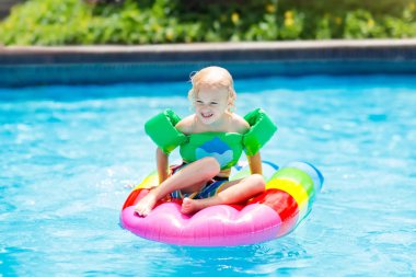 Şişme dondurma float tropikal tatil köyü Açık Yüzme havuzunda mutlu çocuk. Çocuklarla yaz tatili. AIDS yüzmek ve çocuklar için giyim. Su oyuncakları. Renkli salda yüzen küçük kız.