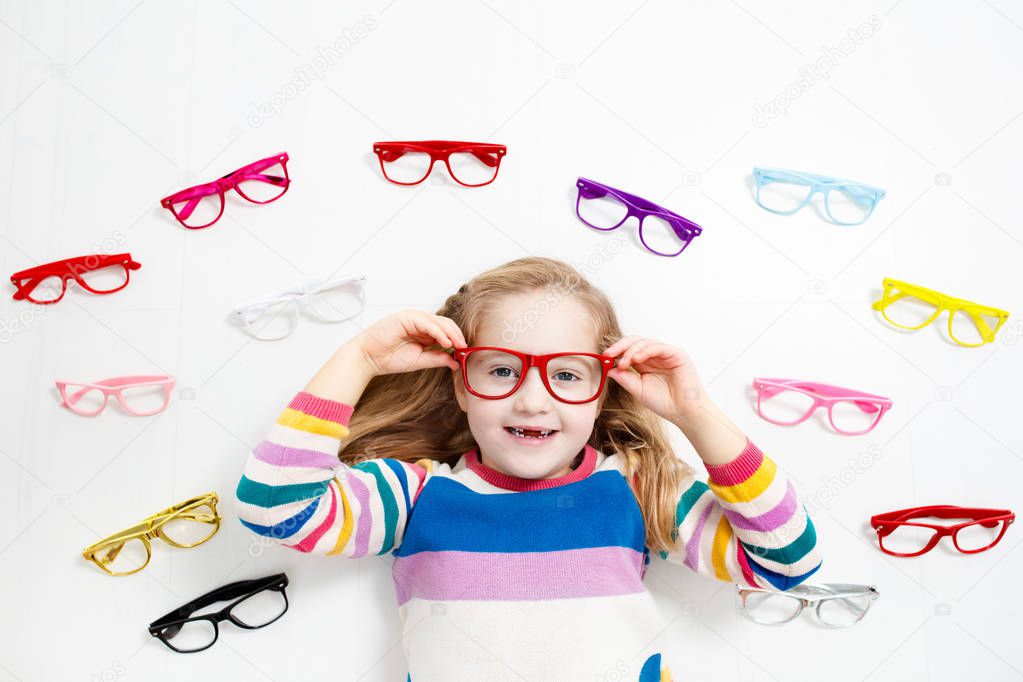Child at eye sight test. Little kid selecting glasses at optician store. Eyesight measurement for school kids. Eye wear for children. Doctor performing eye check. Girl with spectacles at letter chart.