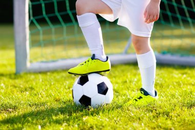 Çocuklar dışarıda futbol oynarlar. Çocuklar futbol maçında gol atıyor. Küçük çocuk topa vuruyor. Formalı ve kramponlu koşan çocuk. Okul futbol kulübü. Genç oyuncu için spor eğitimi.