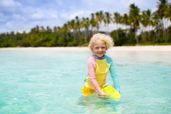 美しいビーチで子供 おもちゃのボートが走って海の海岸でジャンプしている小さな男の子 子供と海の休暇 子供たちは夏のビーチで遊ぶ 水の楽しみ 子供たちは泳ぐ 熱帯島での家族の休日 — ストック写真