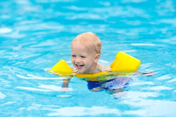 スイミング プールで膨脹可能なアームバンドと赤ちゃん トロピカル リゾートの屋外プールで泳ぐことを学ぶ少年 子供たちと一緒に泳ぐ 子供のための健康的なスポーツ活動 夏休み エイズを泳ぐ — ストック写真
