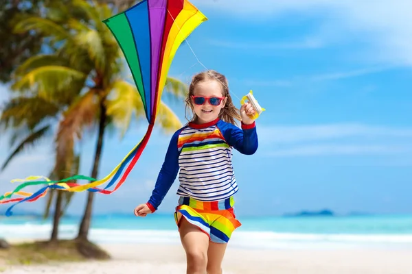 熱帯のビーチのカラフルな凧で実行の子 子供凧虹 小さな女の子がおもちゃの飛行機と海の海岸で遊んで エキゾチックな島の家族の夏休み 子供のための水と砂の楽しみ — ストック写真