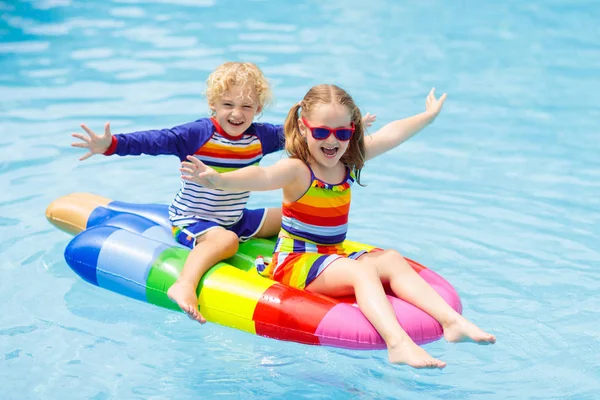 少年と膨脹可能なアイスクリームの女の子は トロピカル リゾートの屋外プールで浮かんでいます 子供たちは夏休み エイズを泳ぐし 子供のために着用します 水のおもちゃ カラフルないかだ浮かぶ小さな子供 — ストック写真
