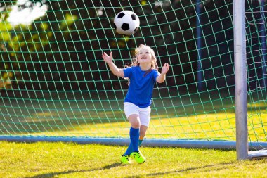 Çocuklar açık sahada futbol oynar. Çocuk futbol maçında bir gol. Küçük kız tekme top. Çocuk çalışan takım forma ve ayakkabısı. Okul futbol kulübü. Spor genç oyuncu için eğitim.