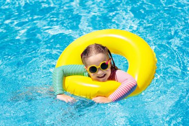 Çocuk yüzme havuzu güneş gözlüklü. Şişme yüzüğü küçük kız. Renkli float evlat. Çocuklar yüzmek ve tropikal resort açık yüzme havuzunda dalış öğrenin. Güneş koruma ve göz giymek. Su eğlenceli.