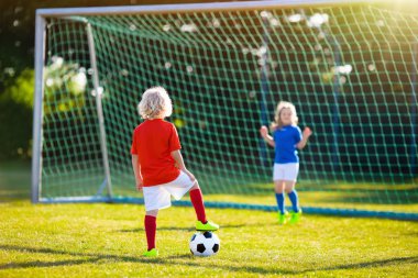 Çocuklar dışarıda futbol oynarlar. Çocuklar futbol maçında gol attılar. Kız ve erkek topa vuruyor. Formalı ve kramponlu koşan çocuk. Okul futbol kulübü. Genç oyuncu için spor eğitimi.