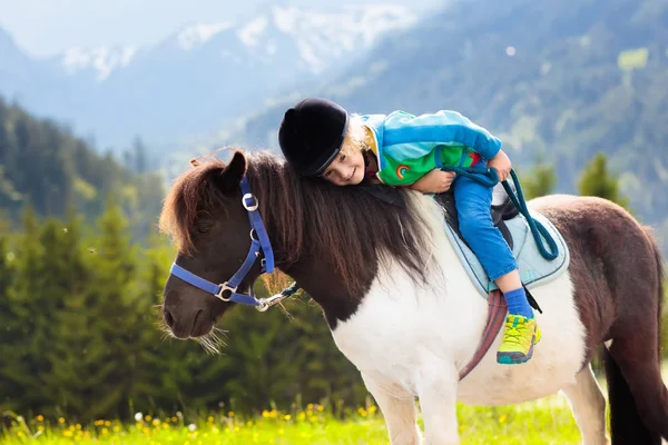 孩子们骑着小马在阿尔卑斯山里在奥地利蒂罗尔的马场度过家庭春假 孩子们骑马 孩子照顾动物 孩子和宠物 骑在马上的小男孩 — 图库照片