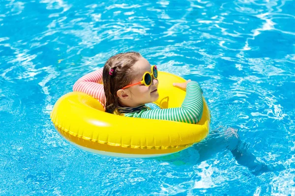 スイミング プールにサングラスを掛けた子 インフレータブルの女の子 カラフルなフロート付きの子供します 子供は泳ぐし トロピカル リゾートの屋外プールでダイビングを学びます 太陽の保護と目を着用します 水の楽しみ — ストック写真