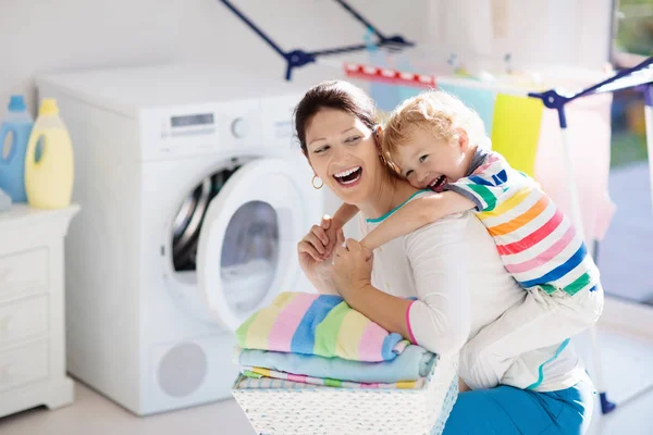 母亲和孩子在洗衣房里用洗衣机或滚筒烘干机 家庭琐事 现代家庭设备和洗涤洗涤剂在白色阳光的家 烘干机架清洗洗衣服 — 图库照片