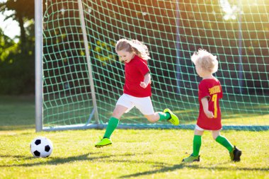 Çocuklar dışarıda futbol oynarlar. Portekiz takım taraftarları. Çocuklar futbol maçında gol attılar. Portekiz formalı ve kramponlu bir kız ve erkek. Futbol sahası. Oyuncu için spor eğitimi.