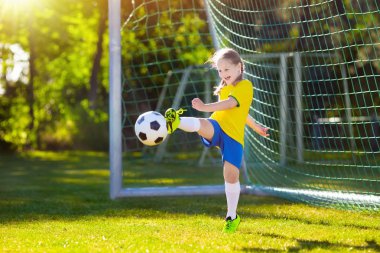 Çocuklar açık sahada futbol oynar. Brezilya takım taraftarları. Çocuk futbol maçında bir gol. Brezilya forması ve ayakkabısı topu tekmeleme, küçük kız. Futbol sahası. Spor oyuncu için eğitim.