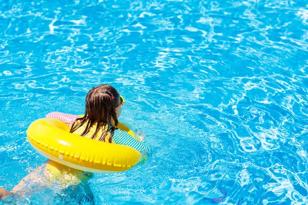 スイミング プールにサングラスを掛けた子 インフレータブルの女の子 黄色のフロート付きの子供します トロピカル リゾートの屋外プールで泳ぐことを学ぶ 太陽の保護と目を着用します あなたのテキストのためのスペース — ストック写真