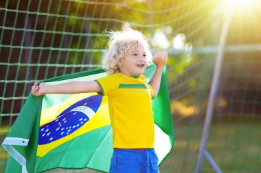 Çocuklar açık sahada futbol oynar. Brezilya ekibi hayranları ile ulusal bayrak. Çocuk futbol maçında bir gol. Çocuk Brezilya forması ve topu tekmeleme falan ezemezsin. Adım, zaferini kutluyor fan.