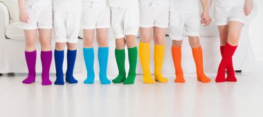 Renkli gökkuşağı çorapları giyen çocuklar. Çocuk ayakkabısı koleksiyonu. Diz boyu çorap ve tayt çeşitleri. Çocuk giysisi ve giysisi. Çocuk modası. Küçük erkek ve kız grubunun bacakları ve ayakları.