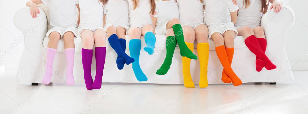 Kids wearing colorful rainbow socks. Children footwear collection. Variety of knitted knee high socks and tights. Child clothing and apparel. Kid fashion. Legs and feet of little boy and girl group.