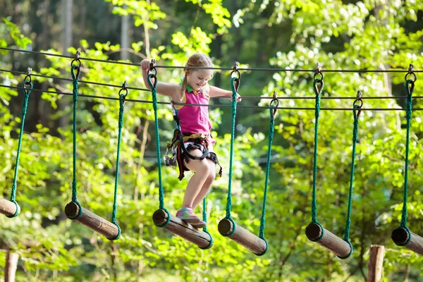 森林探险公园里的孩子孩子们爬上高绳的小径 敏捷性和攀爬户外儿童娱乐中心 小女孩在外面玩 有绳索的学校操场 — 图库照片