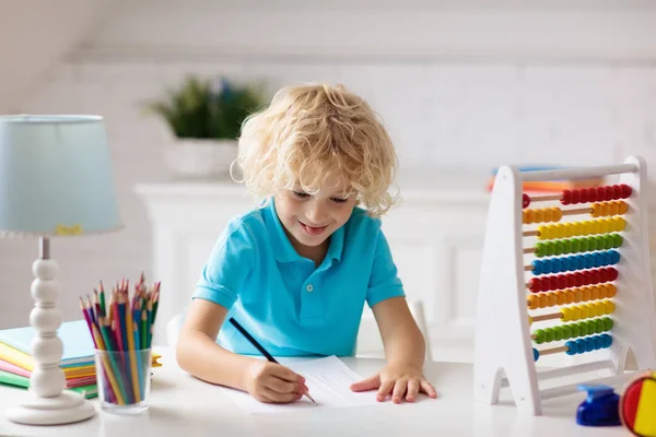 孩子在家里做作业 带着木制彩色算盘的小男孩在做数学练习 学习加法和计数 孩子们学习和学习 学龄前儿童的写作和阅读 回学校去 — 图库照片