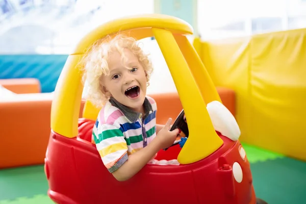 子供のおもちゃの車に乗る 男の子は大きなバスで遊んでいる 屋内遊び場や幼稚園でプラスチックトラックを運転子供 保育室で幼児 男の子のためのおもちゃ デイケアアミューズメントセンター — ストック写真