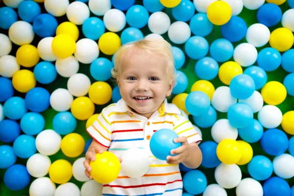 Child playing in ball pit. Colorful toys for kids. Kindergarten or preschool play room. Baby boy at day care indoor playground. Balls pool for children. Birthday party for active preschooler.