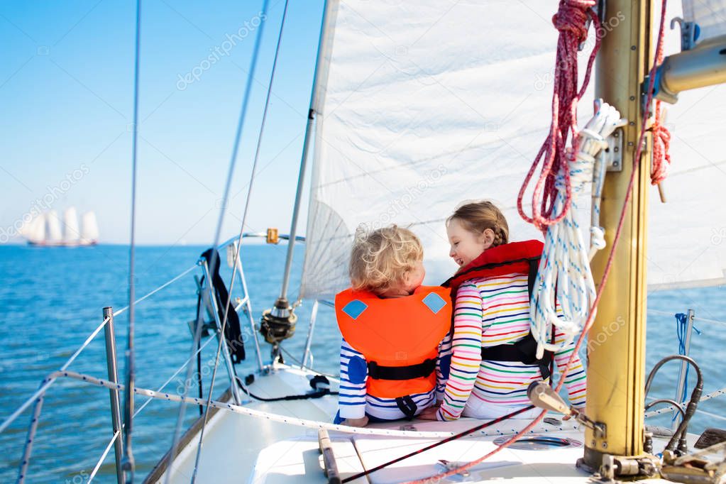 Kids sail on yacht in sea. Child sailing on boat. Little boy and girl in safe life jackets travel on ocean ship. Children enjoy yachting cruise. Summer vacation for family. Young sailors on sailboat.