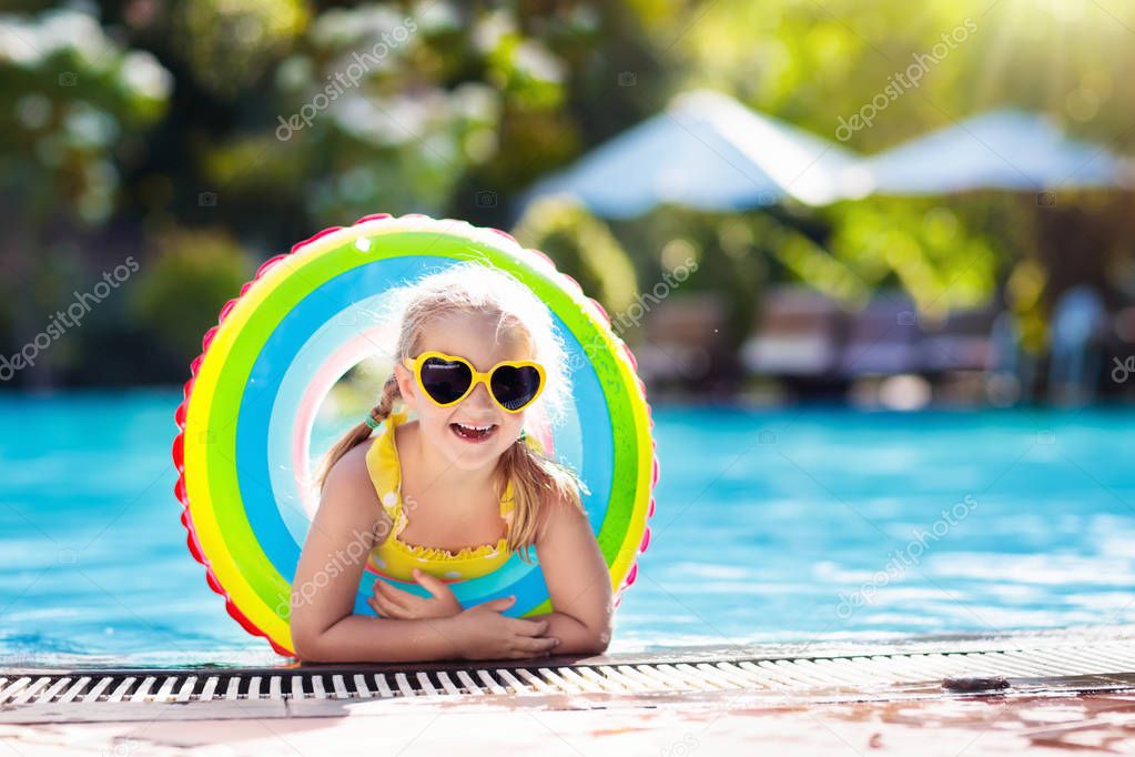 Child with goggles in swimming pool. Little girl learning to swim and dive in outdoor pool of tropical resort. Swimming with kids. Healthy sport activity for children. Sun protection. Water fun.