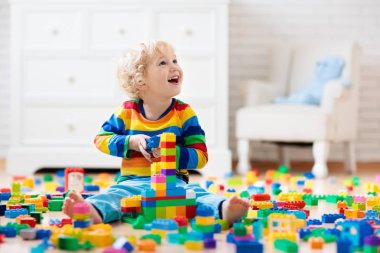 Çocuk renkli oyuncak bloklarıyla oynuyor. Küçük çocuk evde ya da kreşte kule inşa ediyor. Küçük çocuklar için eğitici oyuncaklar. Bebek ya da bebek için inşaat bloğu. Anaokulundaki oyun odasında karışıklık..