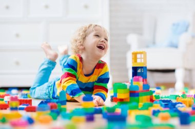 Çocuk renkli oyuncak bloklarıyla oynuyor. Küçük çocuk evde ya da kreşte kule inşa ediyor. Küçük çocuklar için eğitici oyuncaklar. Bebek ya da bebek için inşaat bloğu. Anaokulundaki oyun odasında karışıklık..