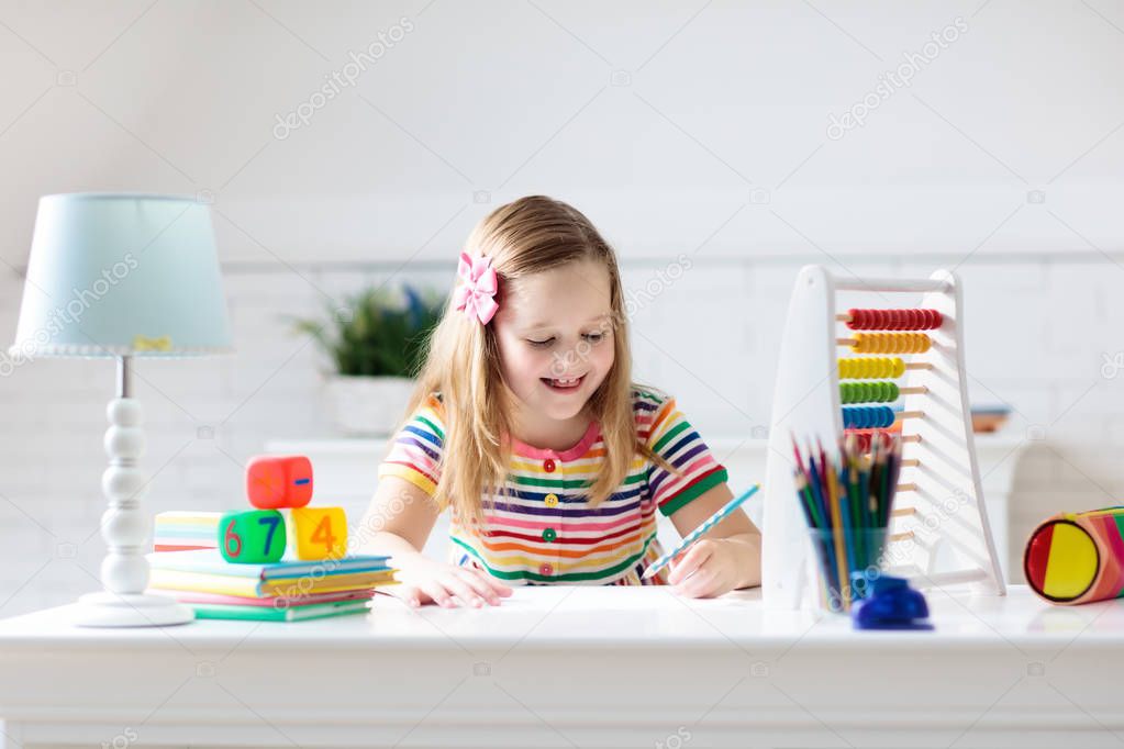 Child doing homework at home. Little girl with wooden colorful abacus doing math exercise learning addition and counting. Kids study and learn. Preschooler kid writing and reading. Back to school.