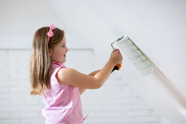 Kids painting attic wall. Home improvement and renovation. Child applying white paint on brick walls in bedroom. Renovating sky parlor with slanted walls. Family moving into new house. — Stock Image Kids Painting Attic Wall Home Improvement Renovation Child Applying White Royalty Free Stock Photos