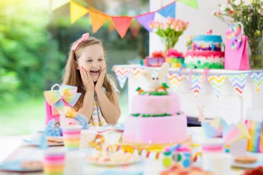 Doğum günü partisi renkli gökkuşağı pastel dekorasyon ve bunny katman pasta ile çocuklar. Küçük kız tatlı, şeker ve meyve ile. Balonlar ve afiş çocuk veya Bebek Doğum günü için şenlikli bir şekilde dekore edilmiş masada.